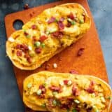 Two butternut squash halves filled with butternut squash, cheese, and bacon.