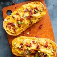 Two butternut squash halves filled with butternut squash, cheese, and bacon.
