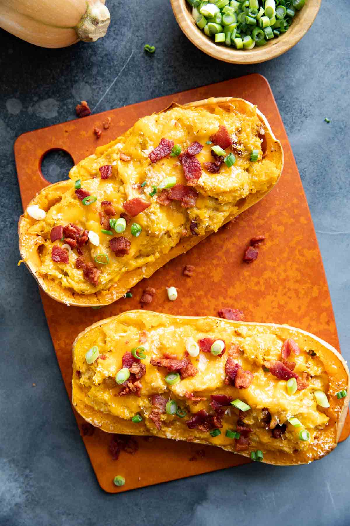Two butternut squash halves filled with butternut squash, cheese, and bacon.