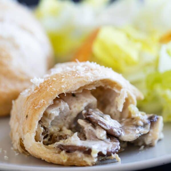 Chicken crescent roll on a plate with a bite taken from it showing the inside.