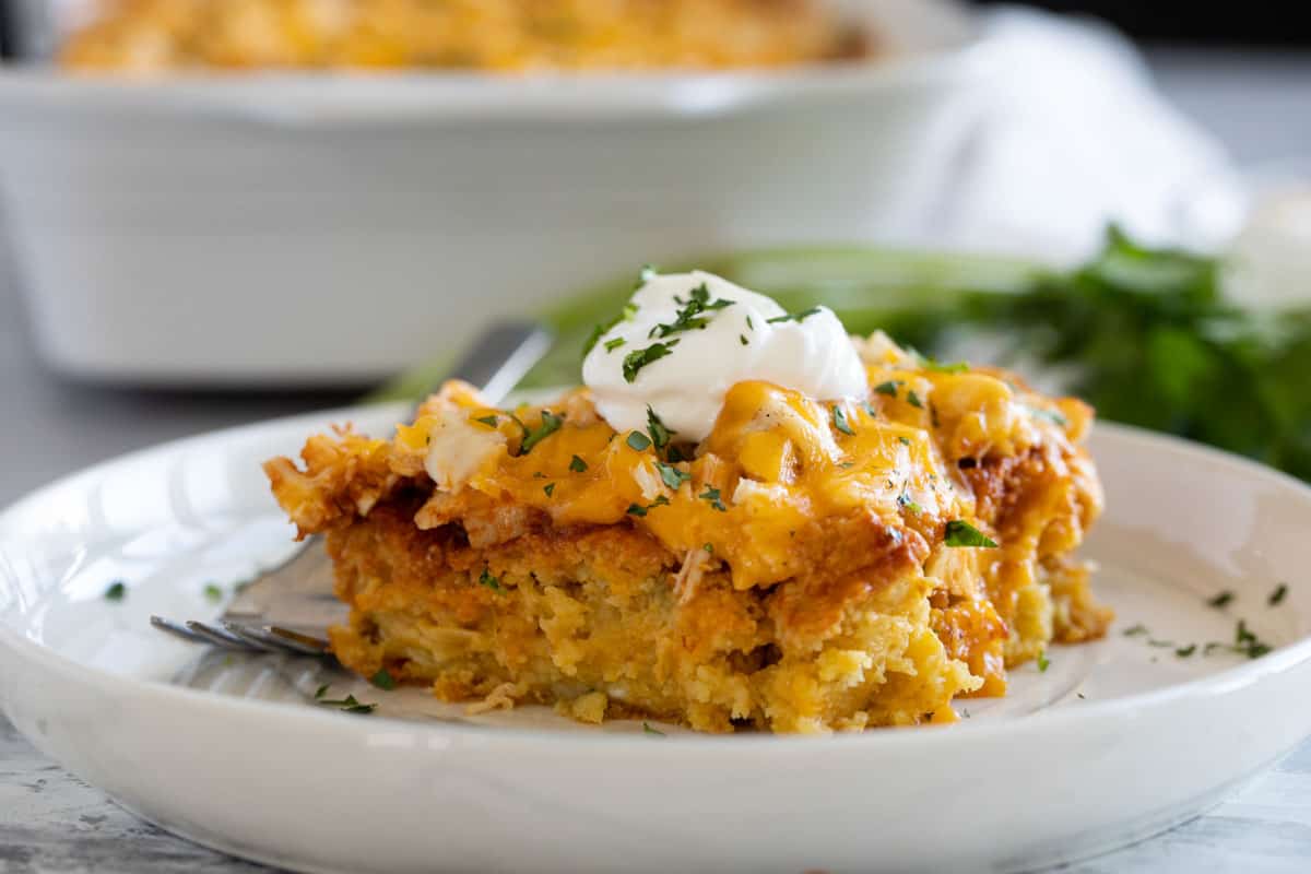 Chicken Tamale Casserole topped with sour cream and cilantro on a plate.