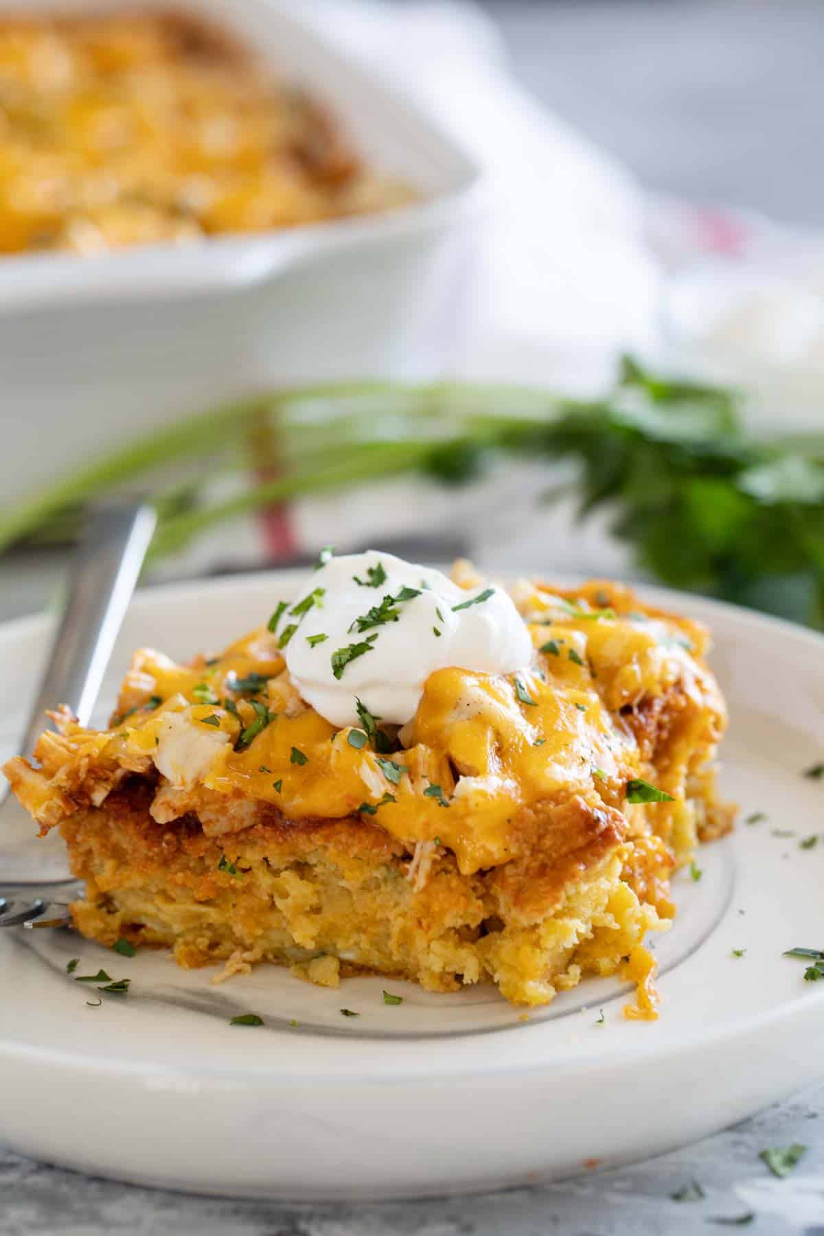 Slice of chicken tamale casserole topped with sour cream.