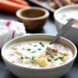 Bowl of ham and potato soup with a spoon in it.