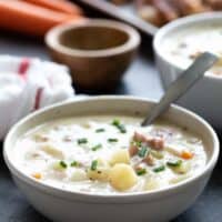 Bowl of ham and potato soup with a spoon in it.