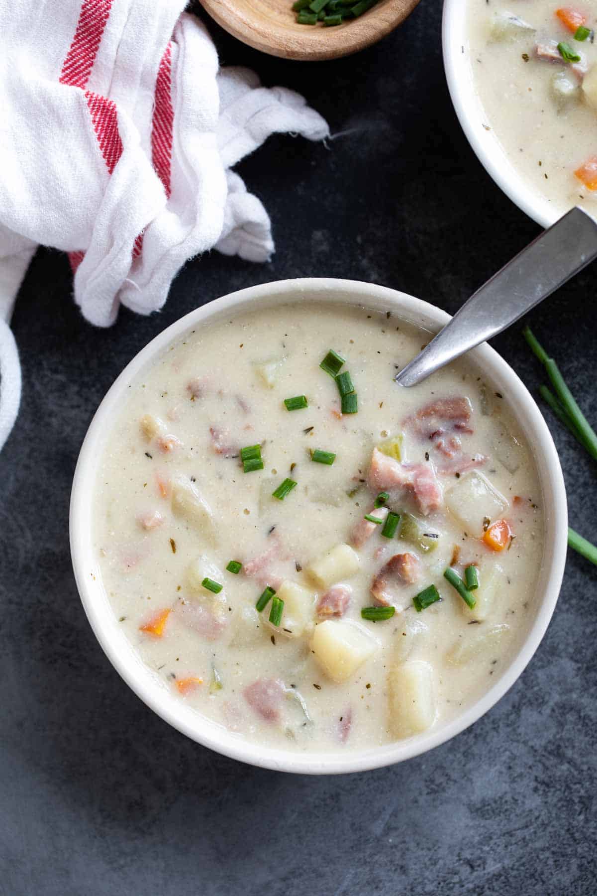 Bowl of ham and potato soup topped with chives.