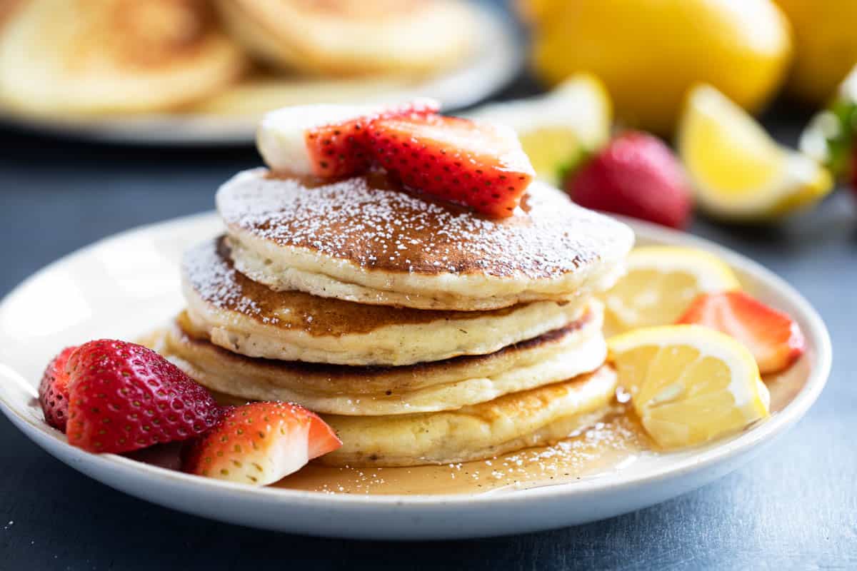Stack of Lemon Ricotta Pancakes topped with strawberries and powdered sugar.