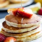 Syrup being poured onto a stack of Lemon Ricotta Pancakes.