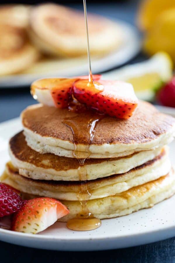Syrup being poured onto a stack of Lemon Ricotta Pancakes.
