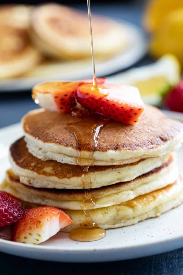 Syrup being poured onto a stack of Lemon Ricotta Pancakes.