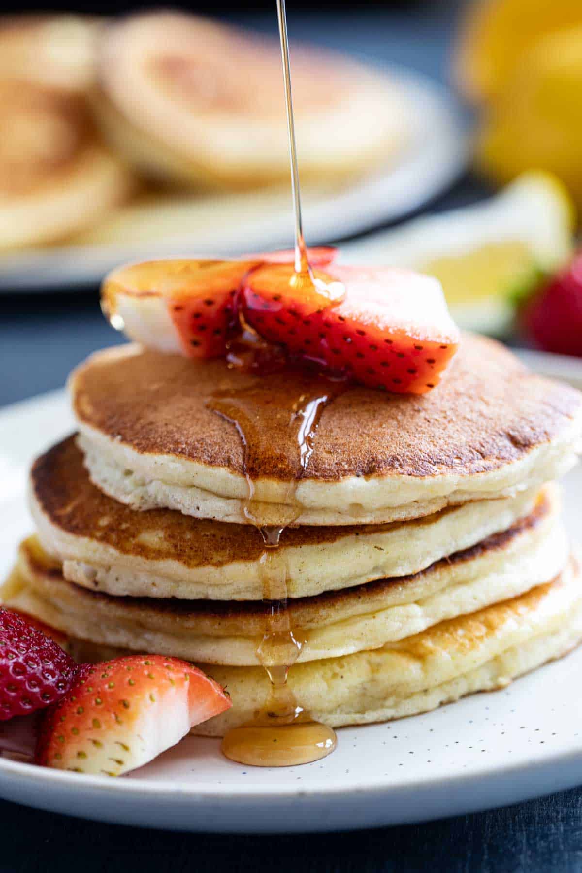 Syrup being poured onto a stack of Lemon Ricotta Pancakes.