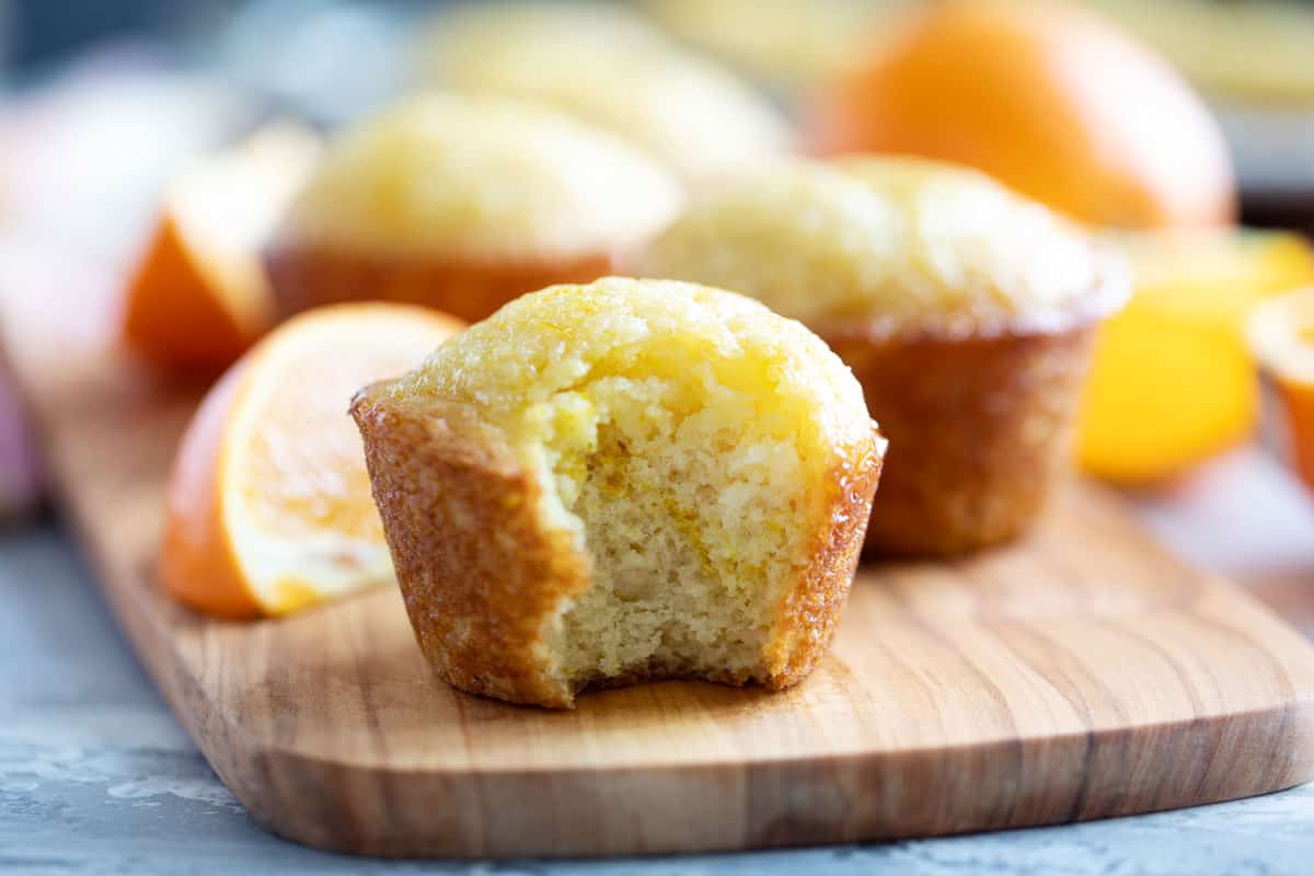 Orange muffin made with fresh orange juice with a bite taken from it.