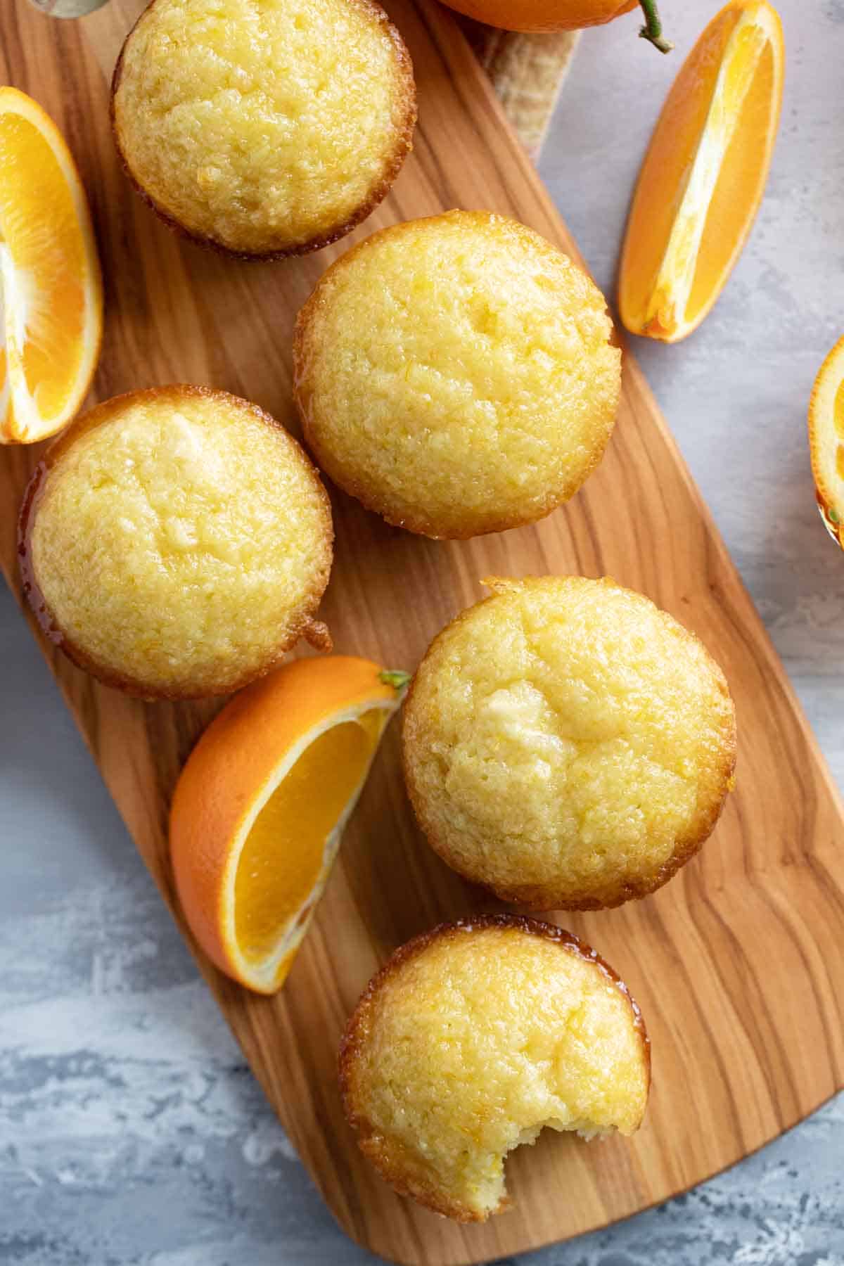 Orange muffins with orange slices on a long cutting board.