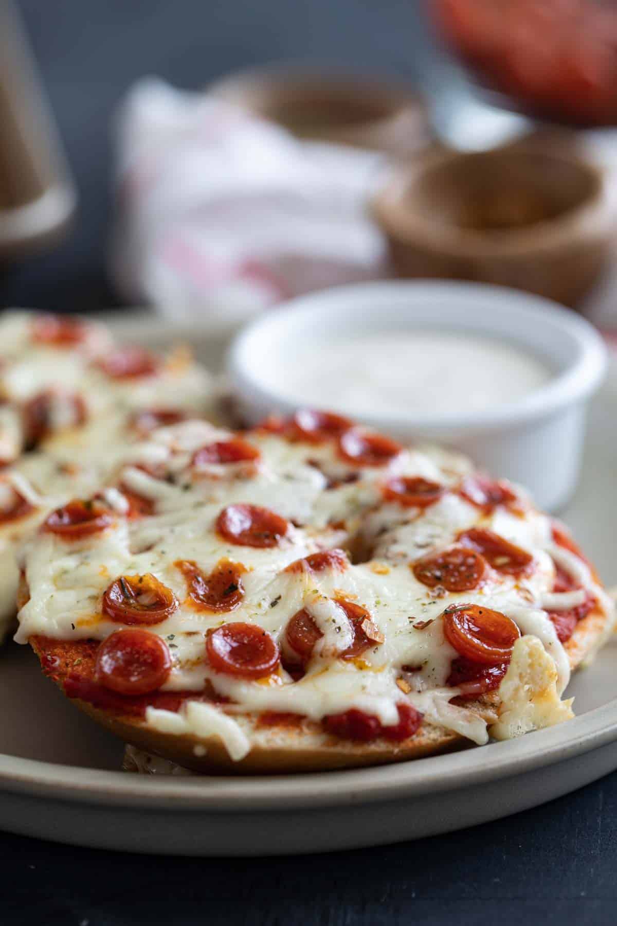 Pizza bagels on a plate with a container of ranch.