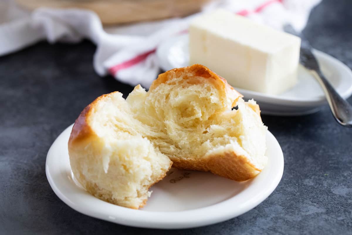 Potato roll on a plate torn in half.