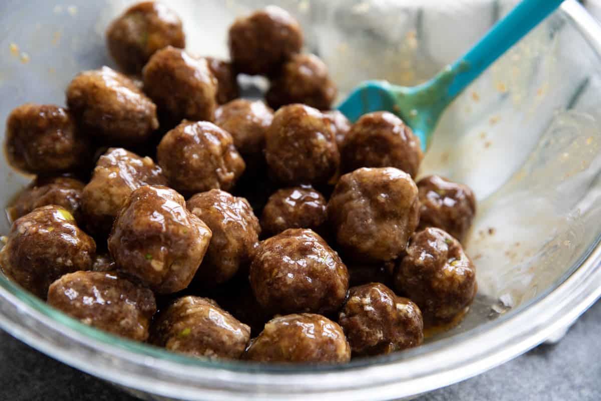 Bowl with meatballs with teriyaki sauce stirred in.