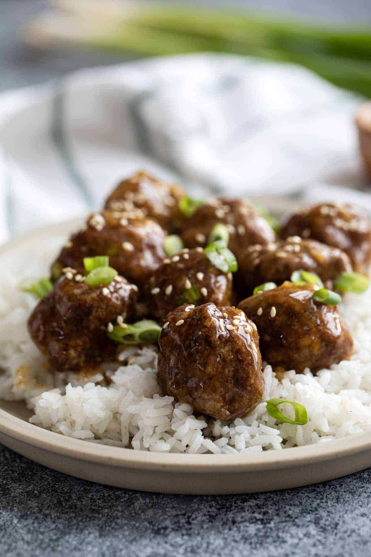 Teriyaki Meatballs and rice topped with green onions and sesame seeds.