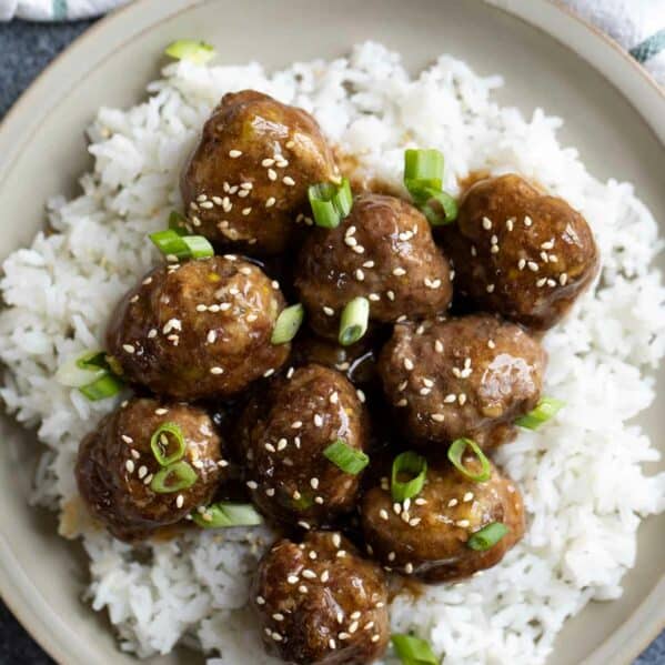 Plate with teriyaki meatballs on top of rice.