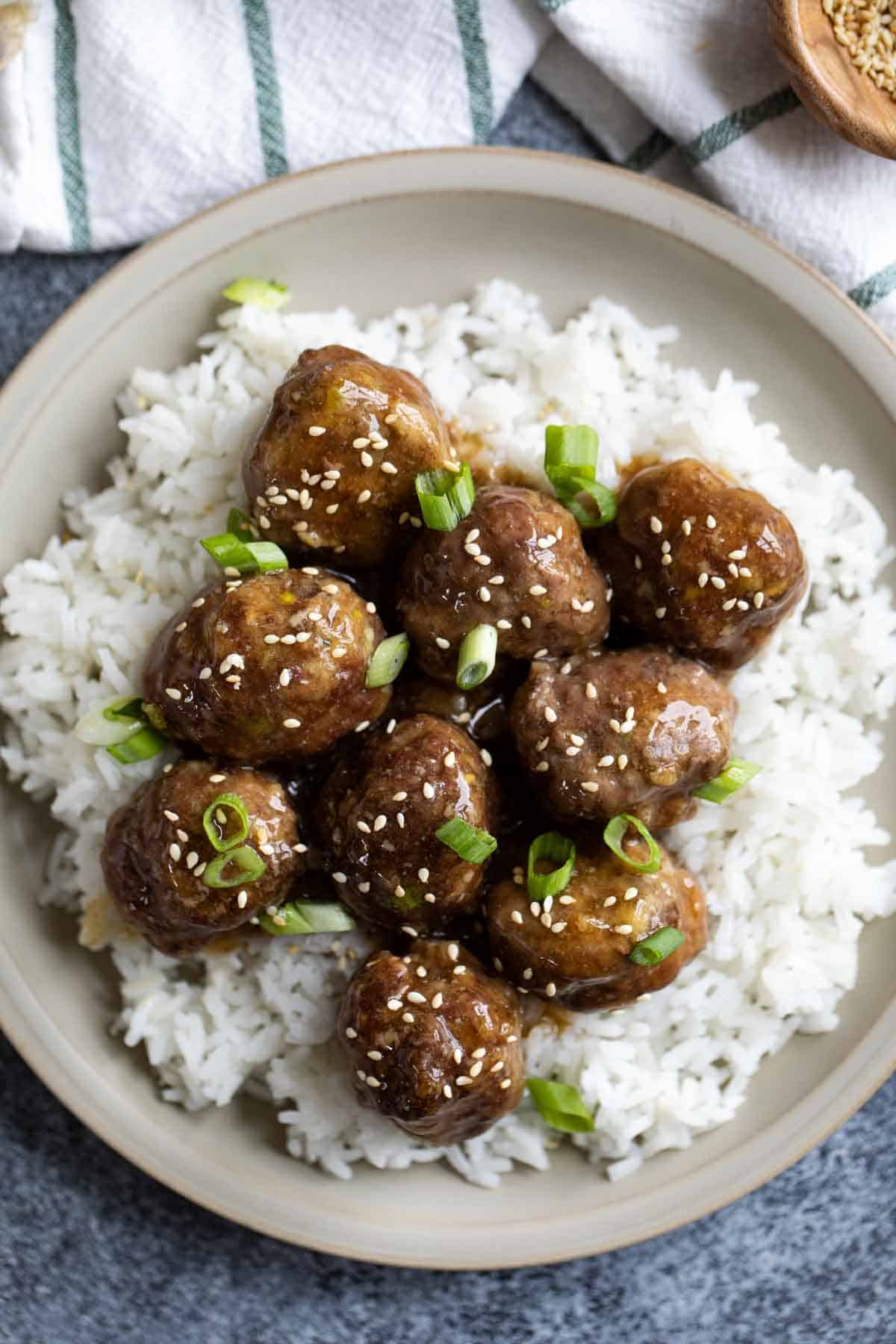 Plate with teriyaki meatballs on top of rice.