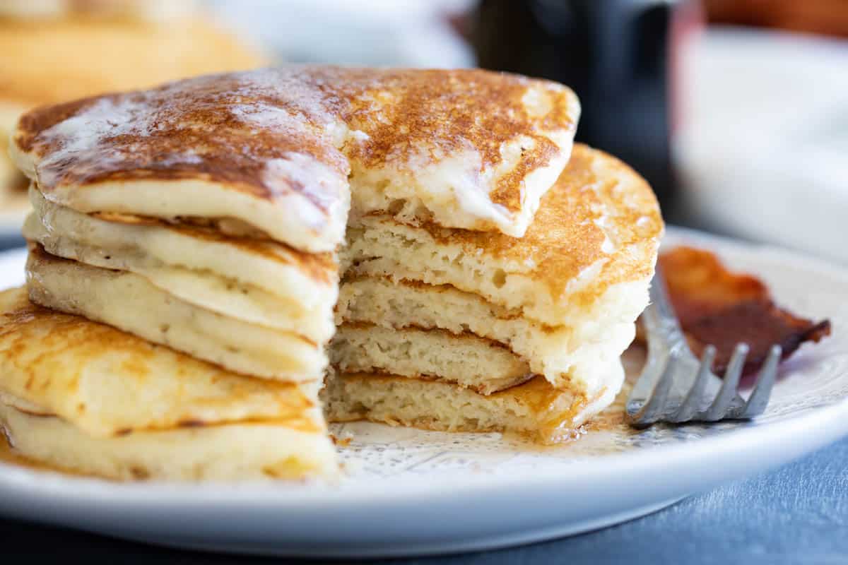 Stack of buttermilk pancakes with a slice taken out of them.
