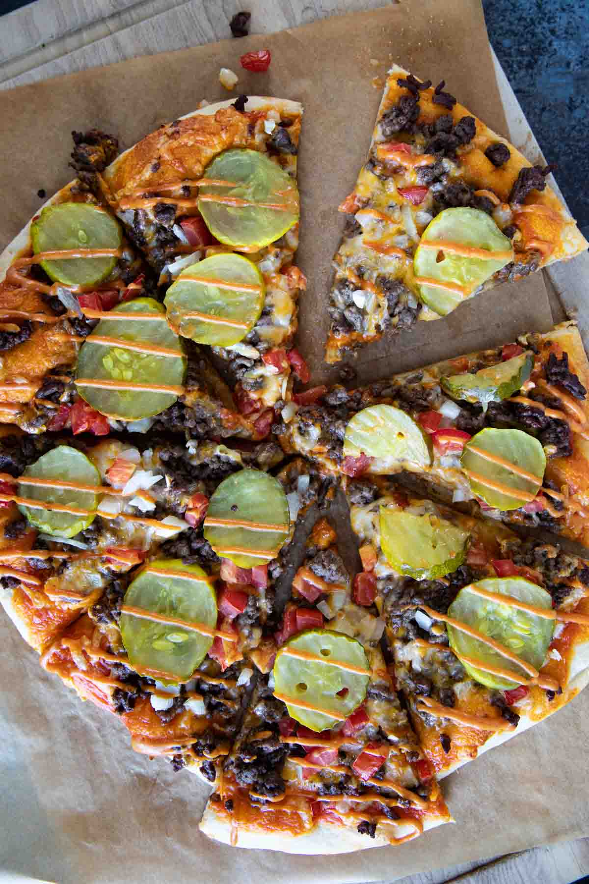 Looking for the ultimate mashup of two classic favorites? Try this Cheeseburger Pizza! This mouthwatering pizza combines all the delicious elements of a cheeseburger, including seasoned ground beef, melted cheese, an easy burger sauce, and tangy pickles, on a perfect pizza crust. Get ready for a taste explosion! Full cheeseburger pizza drizzled with special burger sauce.