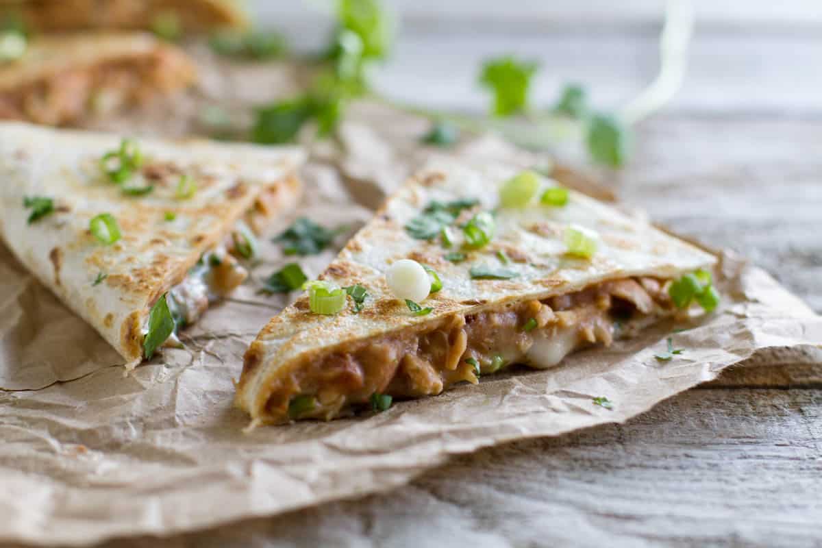 Chicken quesadilla filled with chicken, refried beans, and cheese.