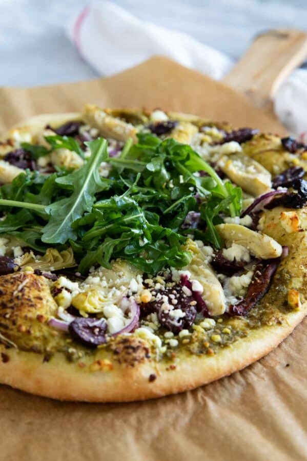 Mediterranean Pizza on parchment paper topped with arugula.