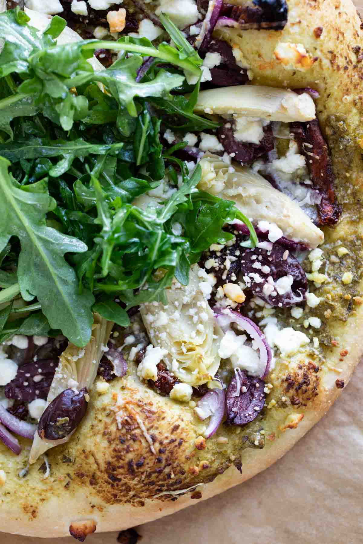 Close up of Mediterranean Pizza with artichokes, olives, and arugula.