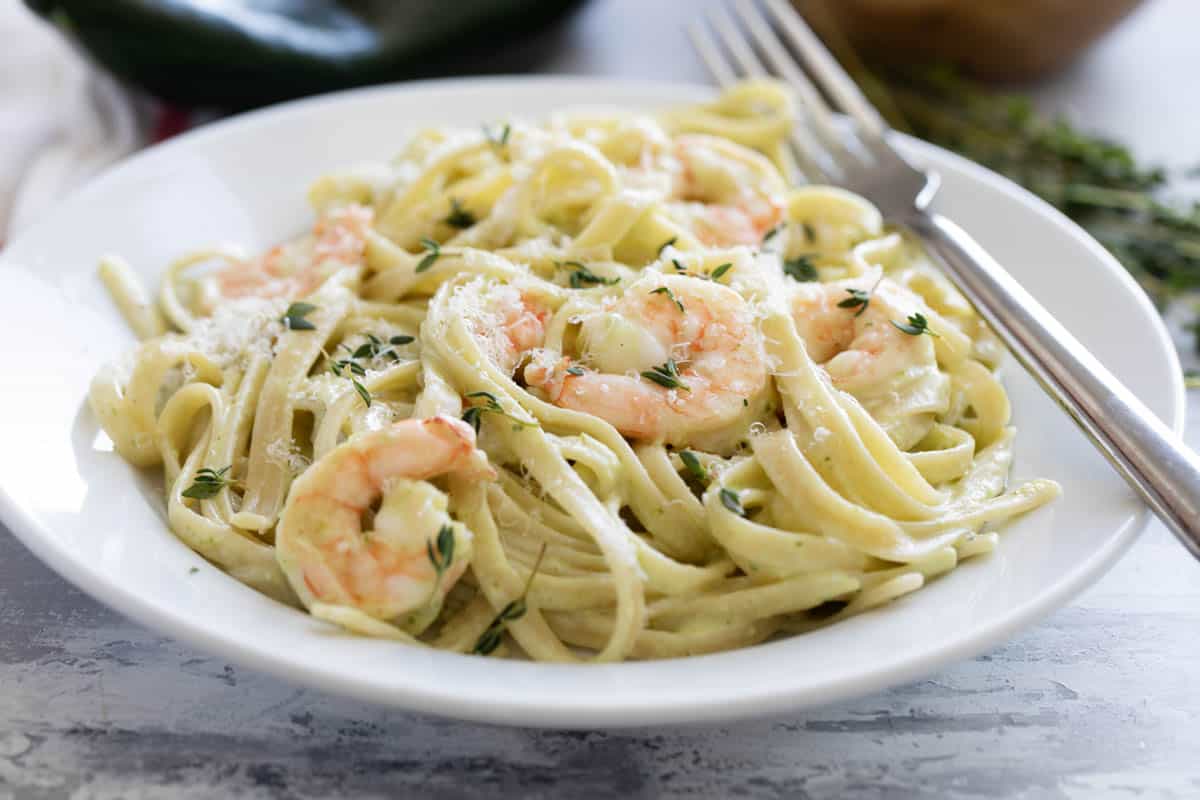 Bowl filled with shrimp pasta with poblano cream sauce with a fork on the side of the bowl.