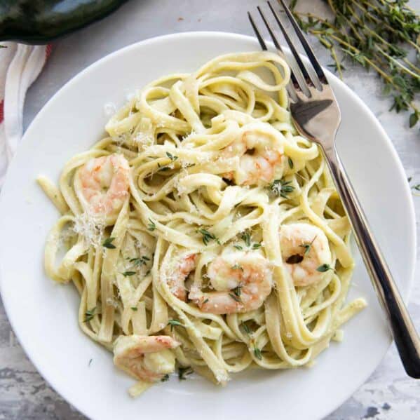 White plate topped with shrimp pasta with poblano cream sauce and a fork.