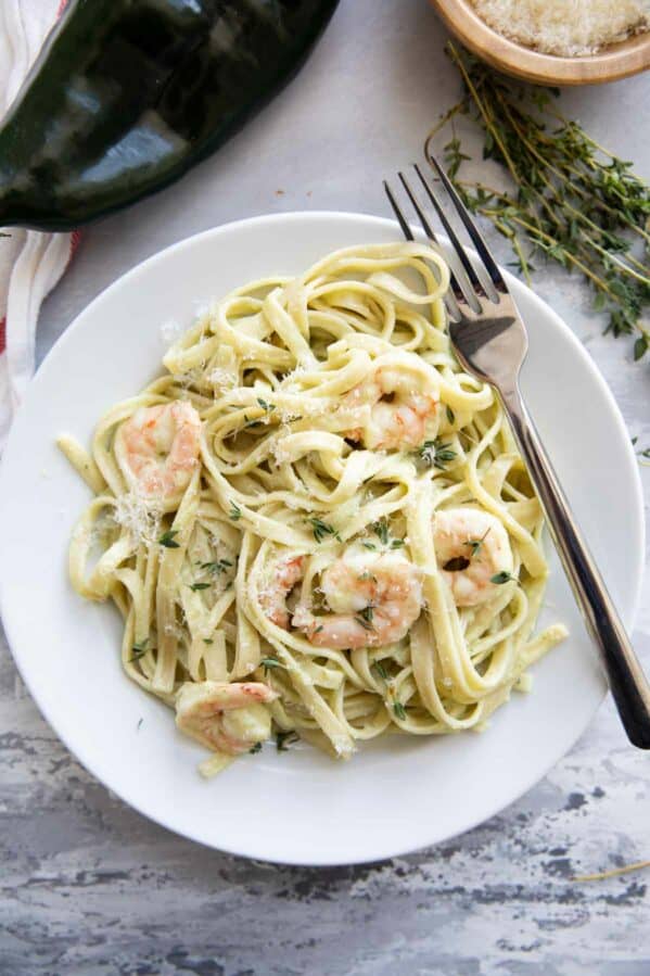 White plate topped with shrimp pasta with poblano cream sauce and a fork.