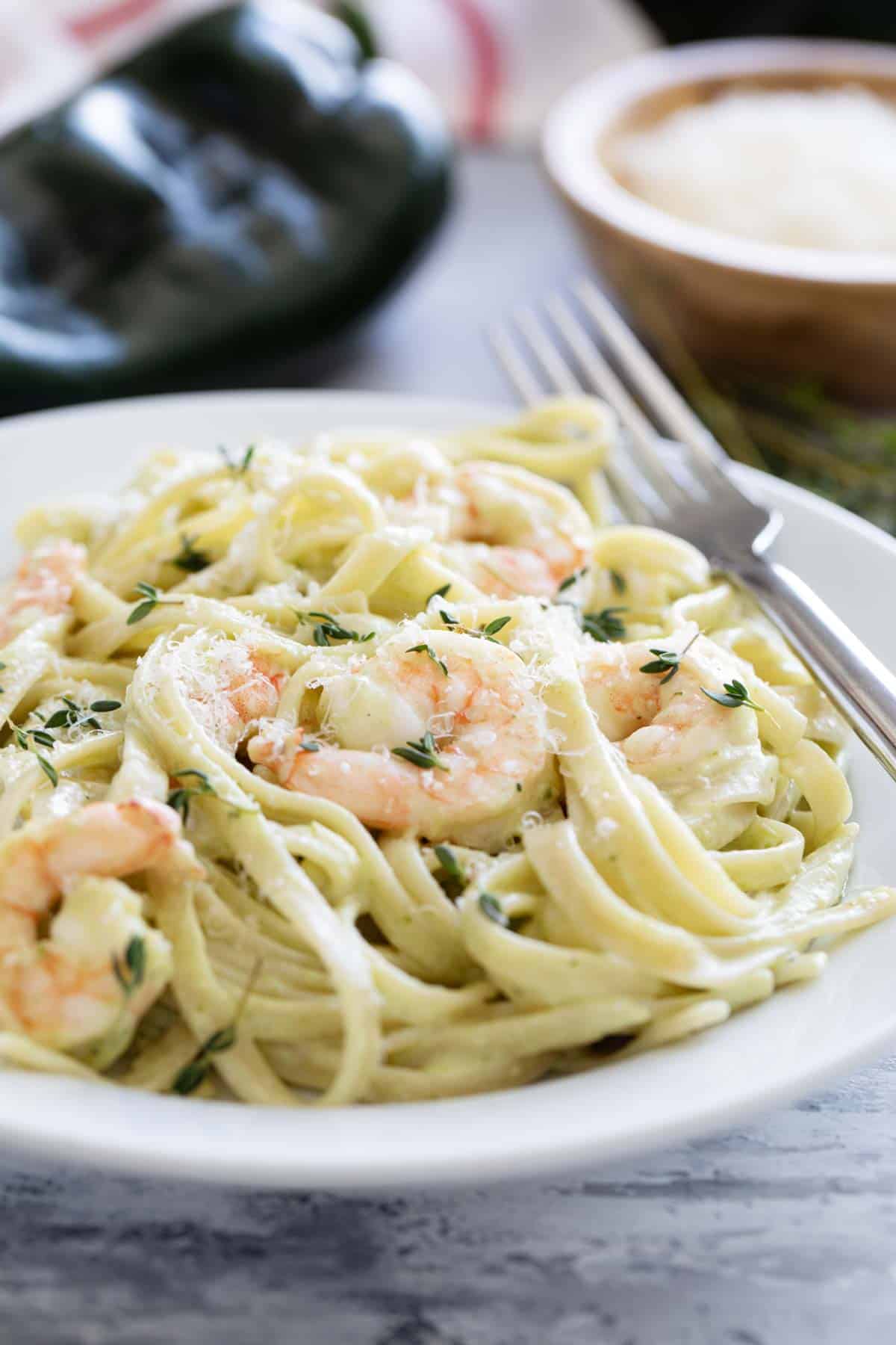 Bowl of shrimp pasta with poblano cream sauce topped with parmesan and fresh thyme.