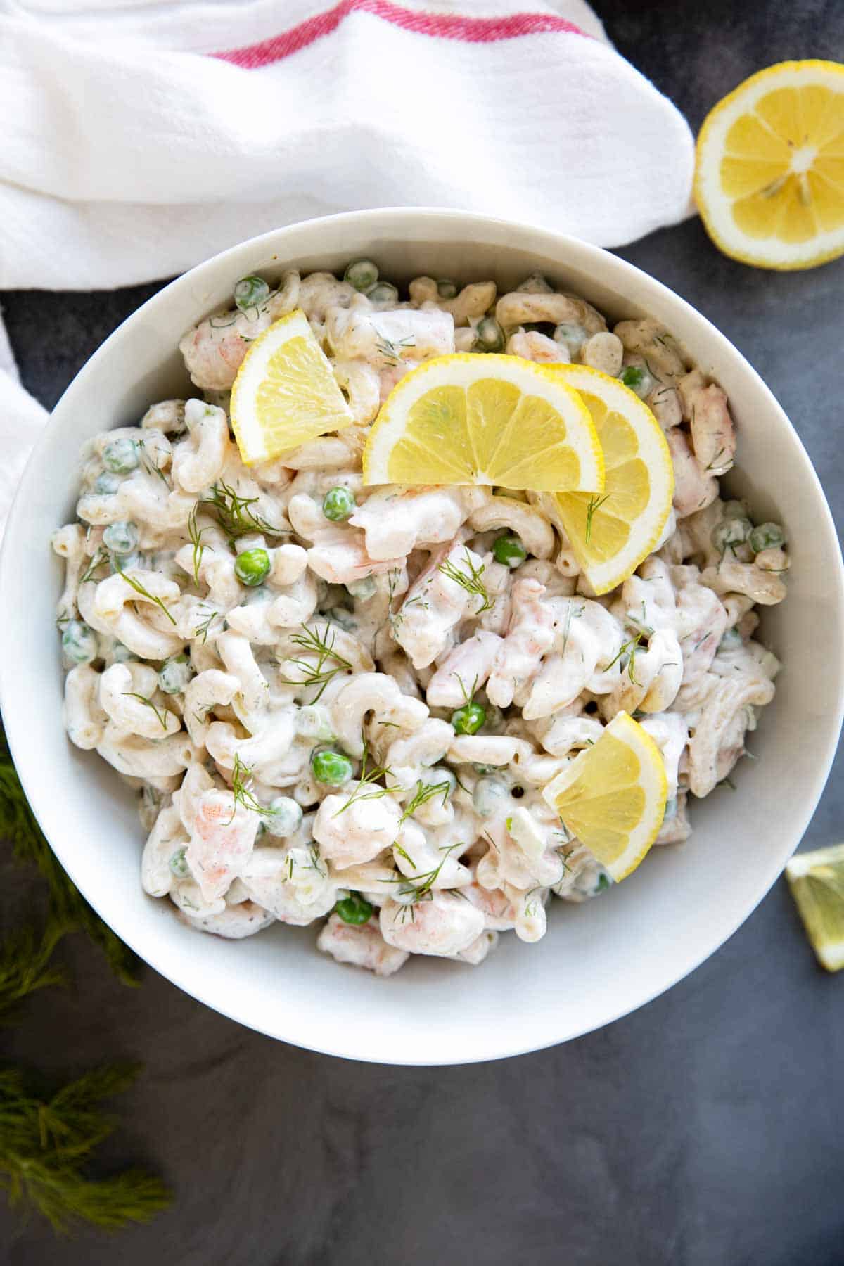 Bowl filled with Shrimp Pasta Salad topped with lemons and dill.