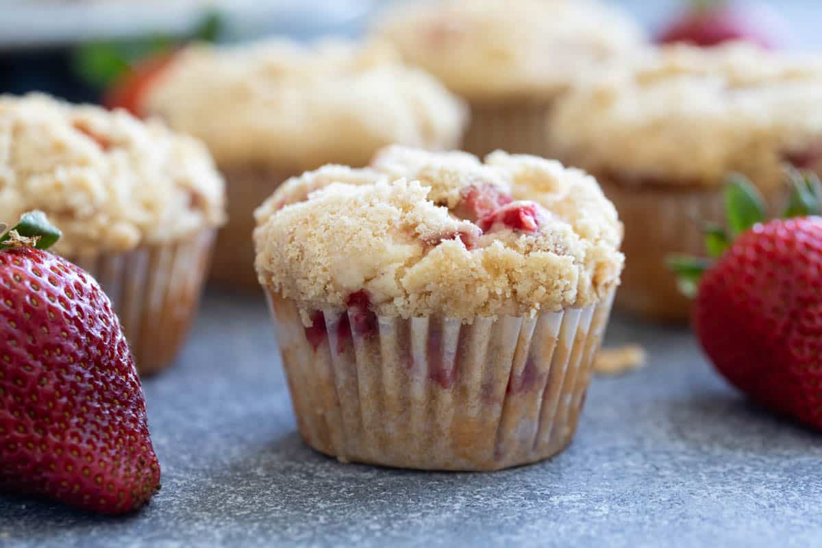 Strawberry muffins with a crumb topping surrounded by fresh strawberries.