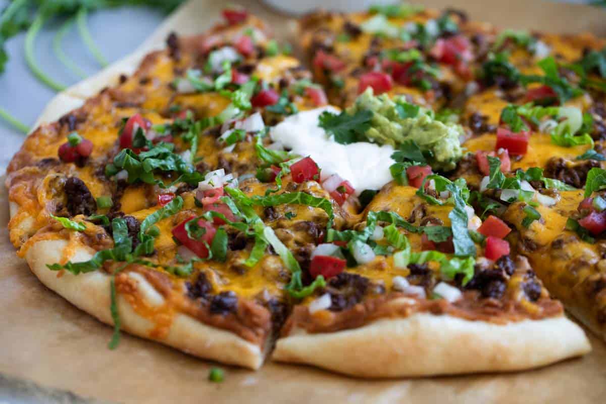 Taco Pizza - pizza topped with beans, taco meat, and taco toppings.