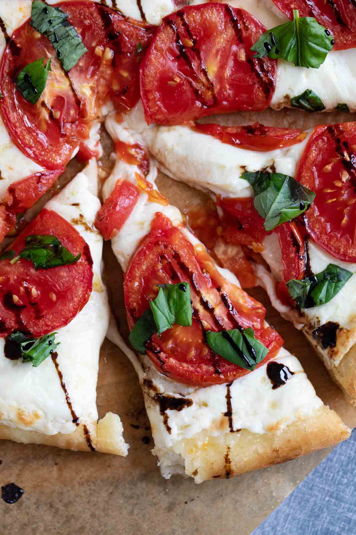 Slices of caprese pizza topped with balsamic glaze.