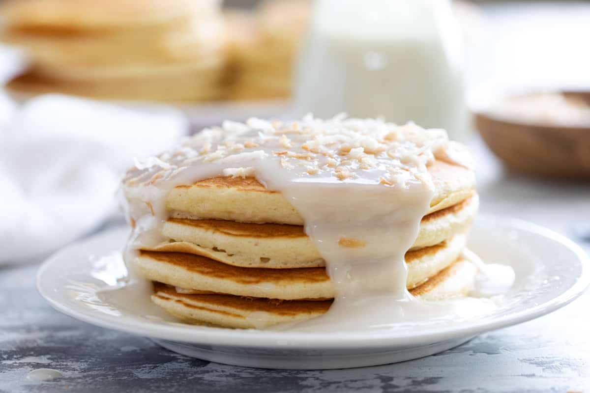 Stack of pancakes topped with coconut syrup and toasted coconut.