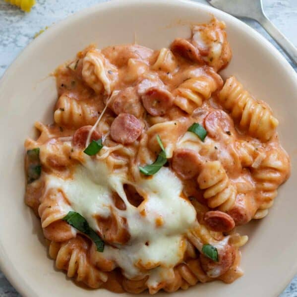 Plate full of pizza pasta with mini pepperoni and mozzarella cheese.