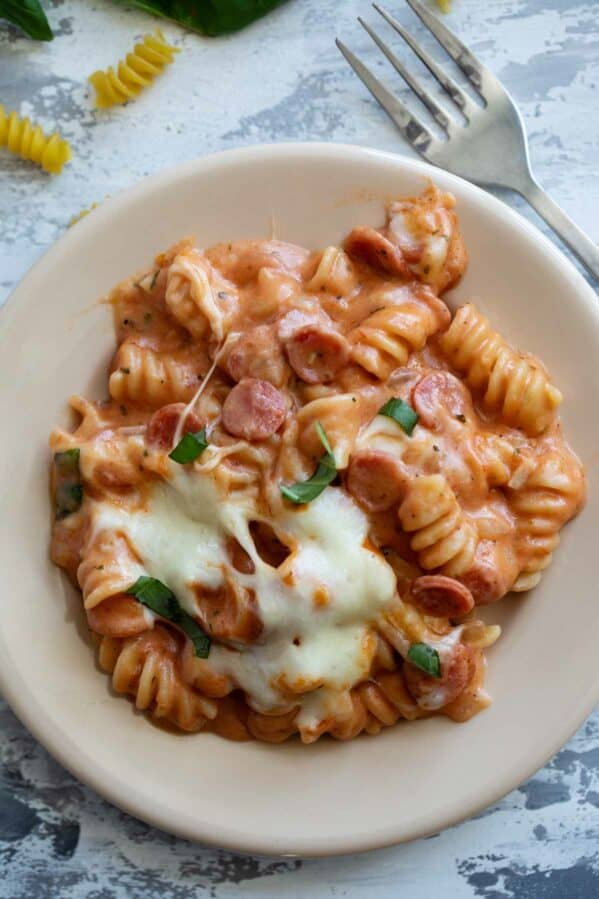 Plate full of pizza pasta with mini pepperoni and mozzarella cheese.