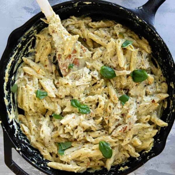 Cast iron skillet filled with chicken pesto pasta.