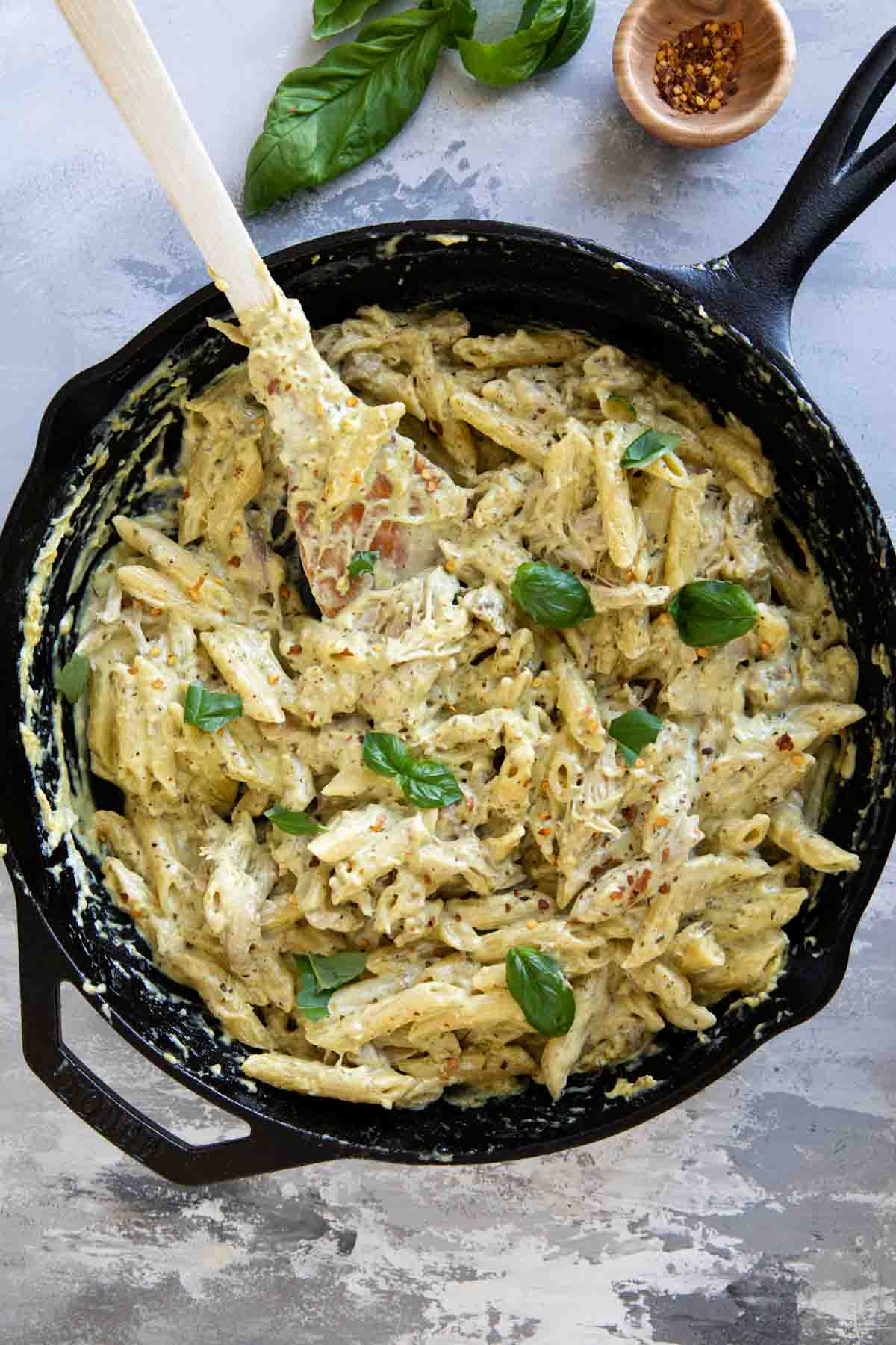 Cast iron skillet filled with chicken pesto pasta.