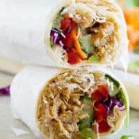 Chicken teriyaki wrap cut in half with halves stacked on top of each other.