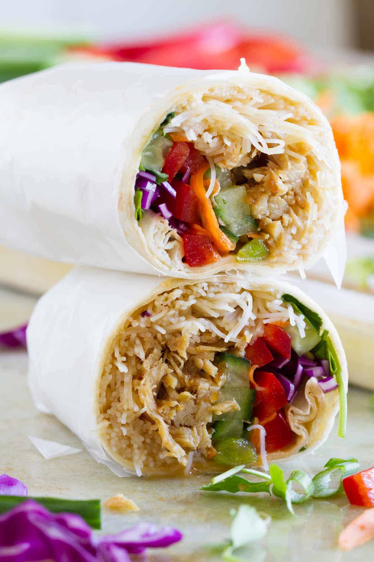 Chicken teriyaki wrap cut in half with halves stacked on top of each other.