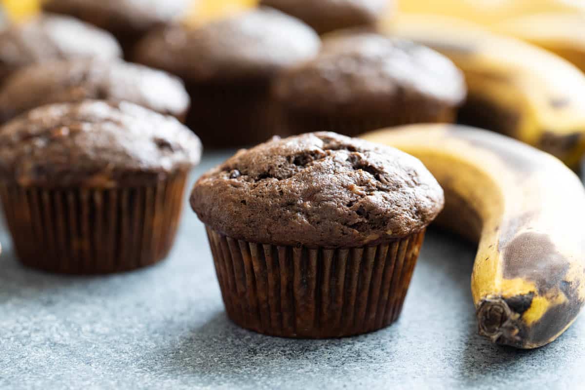 Chocolate Banana Muffins with a ripe banana next to one muffin.