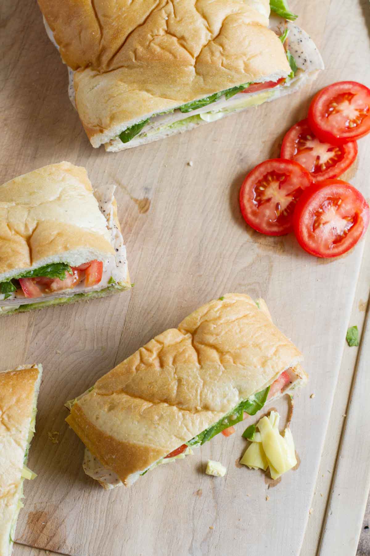 Turkey Sub with Artichokes and Basil cut into portions on a cutting board.