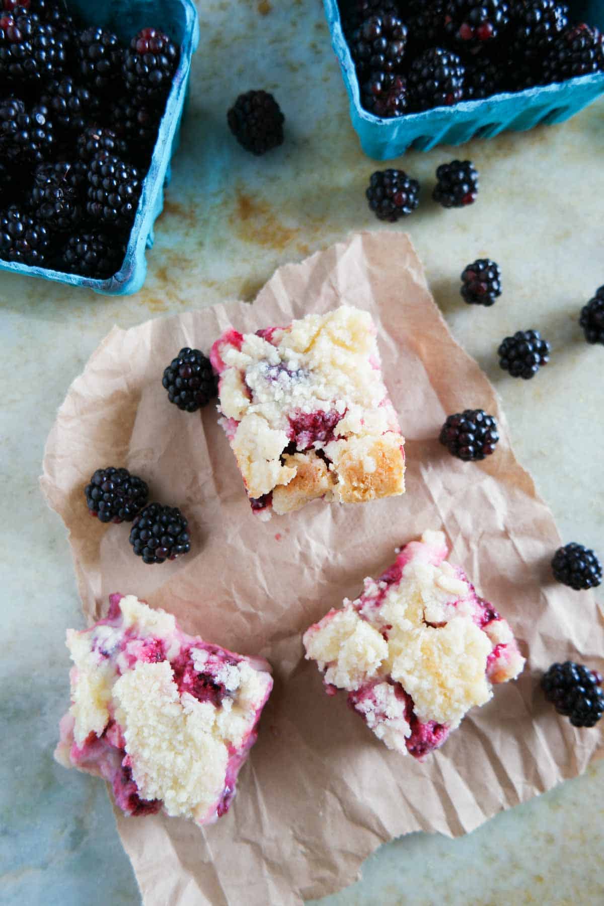 Blackberry pie bars cut into squares with fresh blackberries on the side.