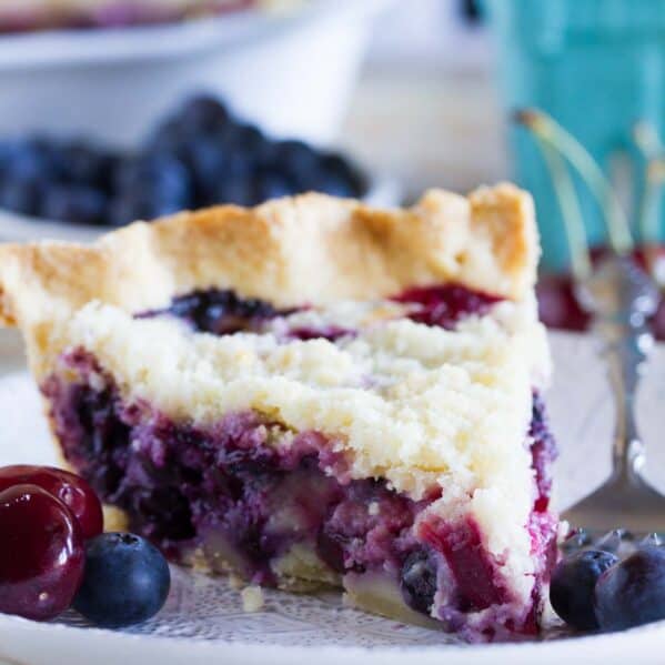 Slice of cherry and blueberry cream pie on a plate.
