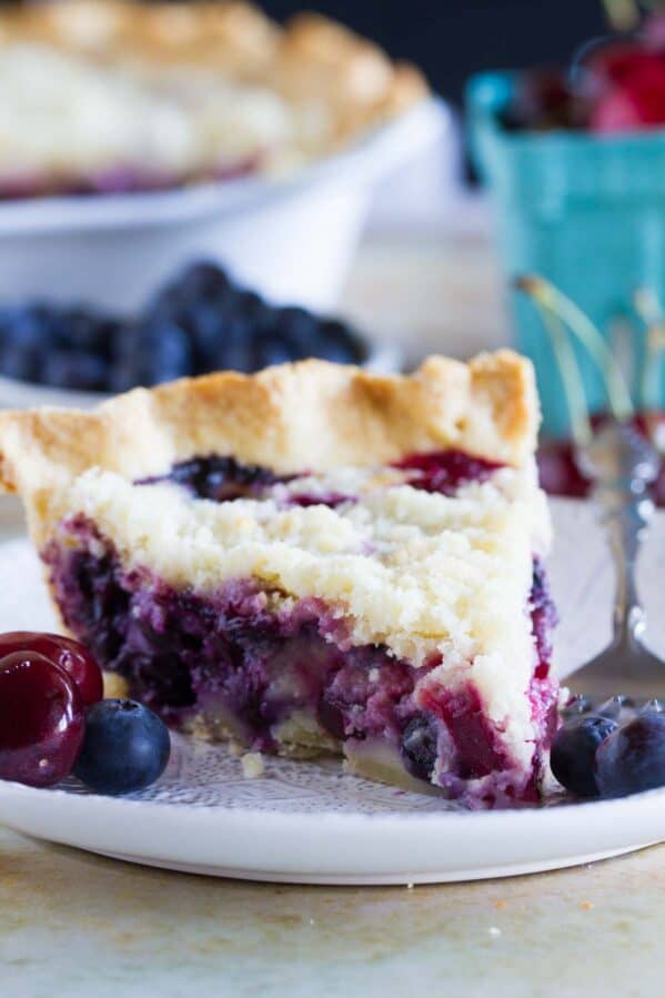 Slice of cherry and blueberry cream pie on a plate.