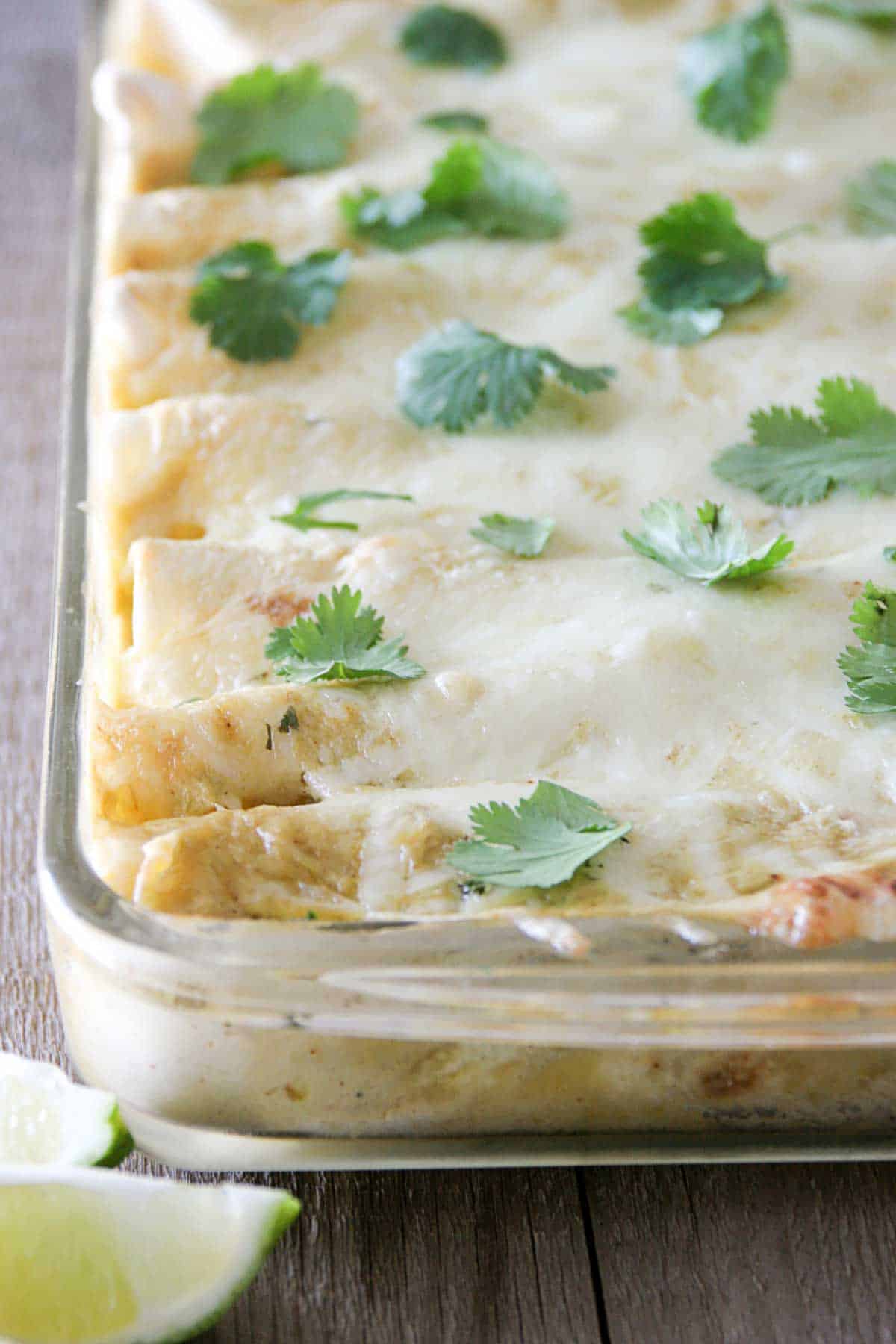 Pan filled with chicken, black bean, and zucchini enchiladas topped with green chile sauce and cheese.