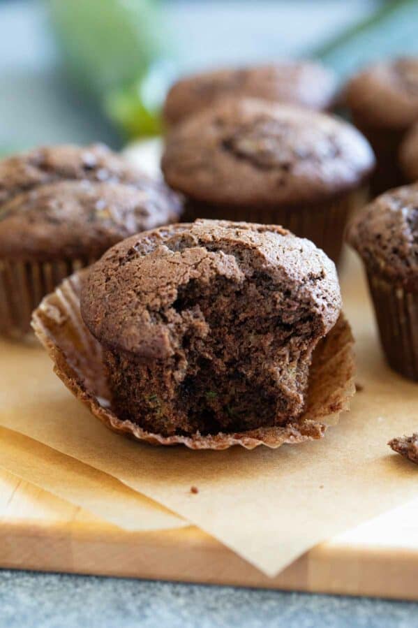 Chocolate zucchini muffin unwrapped with a bite taken from it.