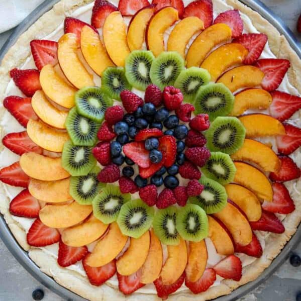 Fruit pizza consisting of a sugar cookie base topped with cream cheese frosting and fresh fruit.